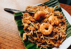 Shrimp Pad Thai noodle dish served on a green banana leaf.